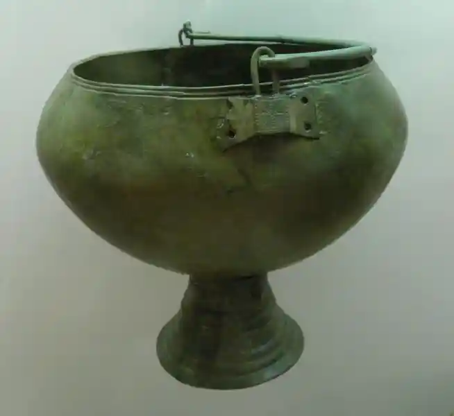 A cross made up of dots on a metal situla